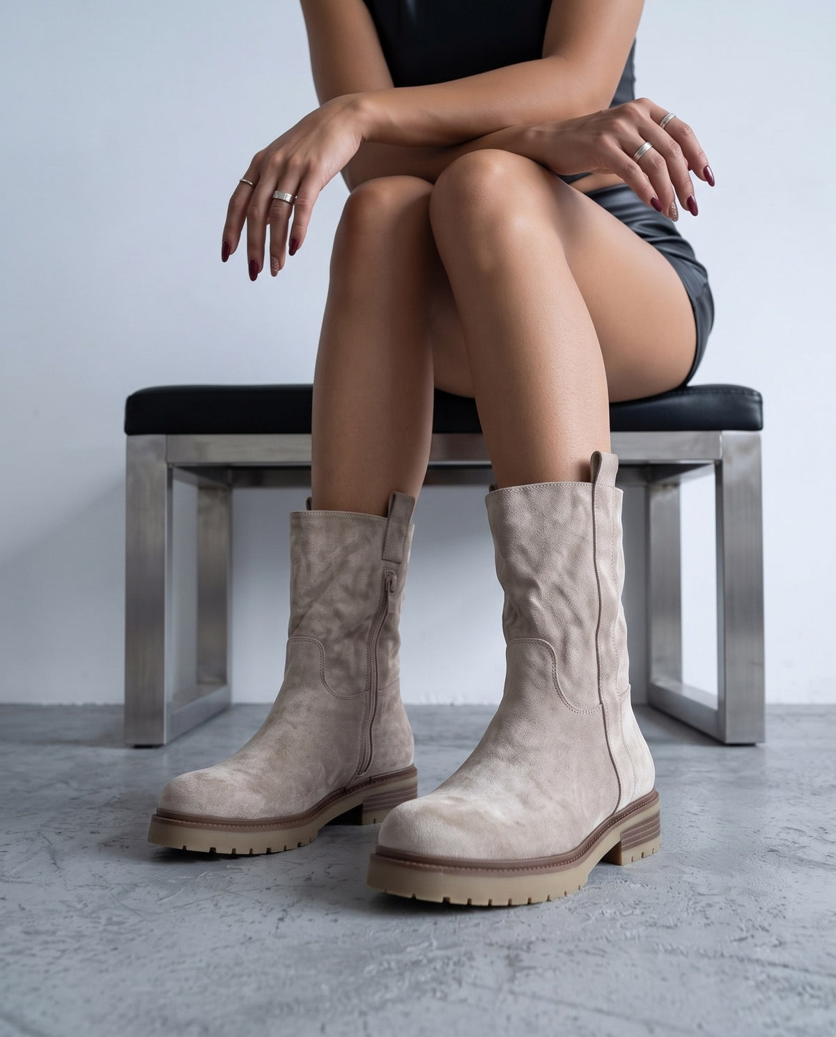 Modella seduta su panca, stivali in camoscio khaki/beige con suola carrarmato in primo piano.