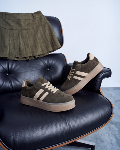 Sneakers donna in ecocamoscio verde con bande beige e suola gum su poltrona in pelle