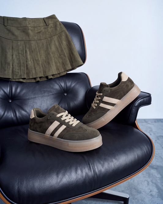 Sneakers donna in ecocamoscio verde con bande beige e suola gum su poltrona in pelle