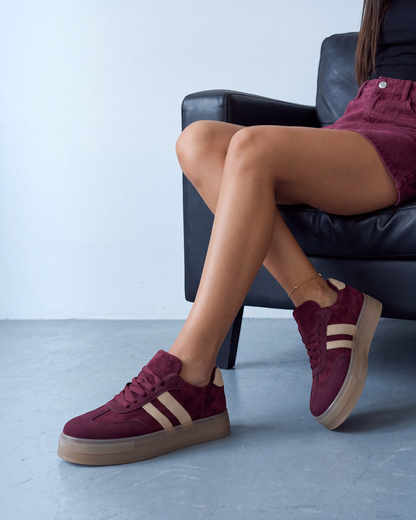 Sneakers donna in ecocamoscio bordeaux con bande beige e suola gum, indossate seduta - foto 3